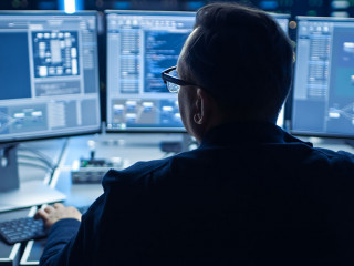 Professional IT Programer Working in Data Center on Desktop Computer with Three Displays, Doing Development of Software and Hardware. Displays Show Blockchain, Data Network Architecture Concept