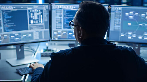 Professional IT Programer Working in Data Center on Desktop Computer with Three Displays, Doing Development of Software and Hardware. Displays Show Blockchain, Data Network Architecture Concept