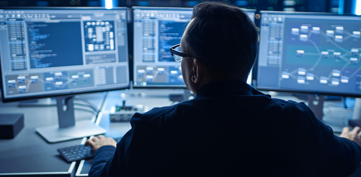 Professional IT Programer Working in Data Center on Desktop Computer with Three Displays, Doing Development of Software and Hardware. Displays Show Blockchain, Data Network Architecture Concept