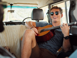 Man with guitar, music in van and smile on travel vacation road trip together with friends. Group holiday in summer, relax and happy musician singing with instrument on a countryside safari adventure