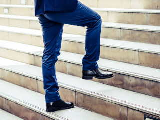 Close up of young businessman walking upstairs outside office.