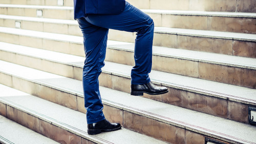 Close up of young businessman walking upstairs outside office.
