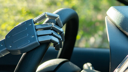 Robot arm on a steering wheel. Artificial intelligence drives a car. Autonomous vehicle concept.