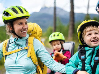 Family with small children cycling outdoors in summer nature.