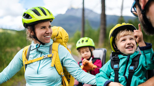 Family with small children cycling outdoors in summer nature.