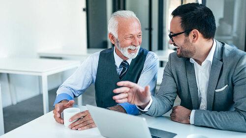 Smiling senior and junior business men at work.