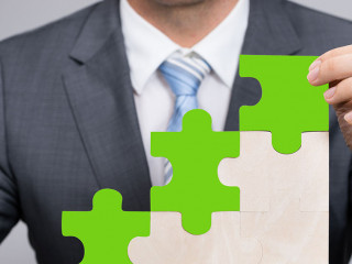 Businessman Holding Jigsaw Graph On Grass