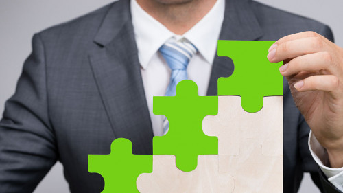 Businessman Holding Jigsaw Graph On Grass