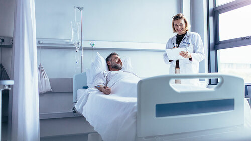 Doctor attending sick patient in hospital bed
