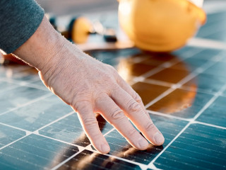 Hands, engineer and solar panel in construction for renewable energy, electricity or technology. Hand of electrician or technician feeling heated plates for quality, sun or testing power on building