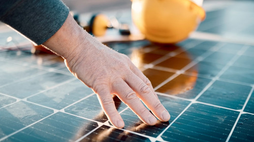 Hands, engineer and solar panel in construction for renewable energy, electricity or technology. Hand of electrician or technician feeling heated plates for quality, sun or testing power on building