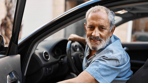 Senior grey-haired man smiling confident opening car door at street
