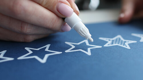 Female hand crossing out service quality rating stars with white marker closeup