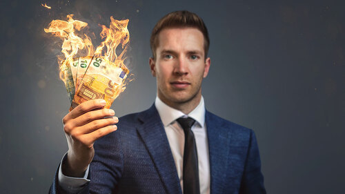 Businessman holding burning money in his hand
