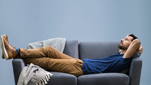 Man Relaxing On Sofa At Home