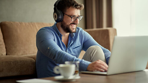 man with headphones using laptop in his home