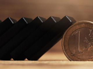 Chain of black domino tiles falling stopped by a one euro coin.