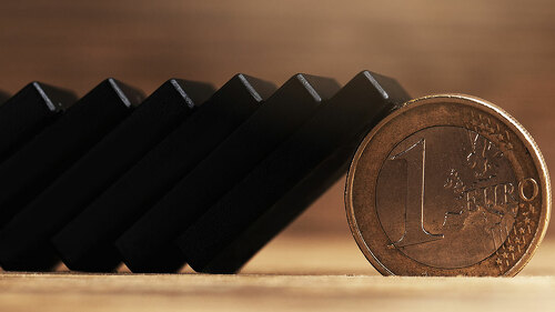 Chain of black domino tiles falling stopped by a one euro coin.
