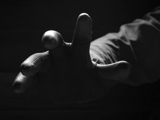 Front view of the scary hand of mysterious criminal in black glo