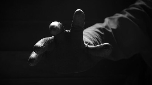 Front view of the scary hand of mysterious criminal in black glo