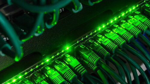 Close up of green network cables connected to switch glowing in the dark