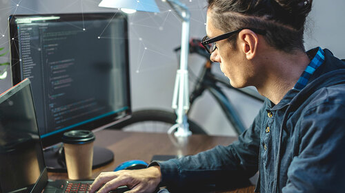 Male programmer is writing program code on a laptop at home. The concept of software development