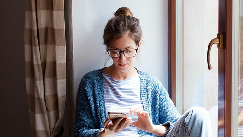 Young woman working from home office. Freelancer using laptop, phone and the Internet.