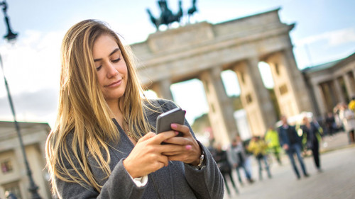 Beautiful girl text messaging while standing near Brandenburg Gate in Berlin, Germany,