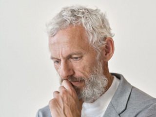 Thoughtful sad senior old business man thinking isolated on white wall.