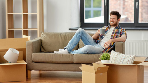 man with boxes and drinking coffee at new home