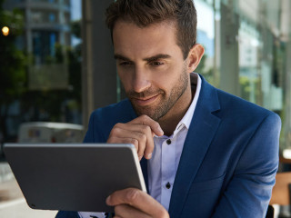 Businessman sitting outside at a cafe table using a tablet