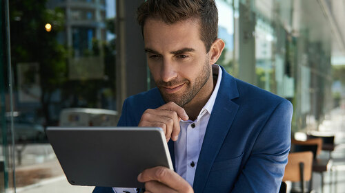 Businessman sitting outside at a cafe table using a tablet