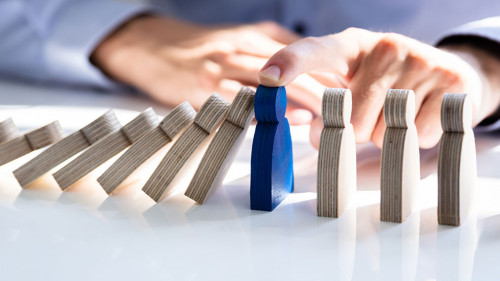 Businessperson Stopping Falling Persons On Desk