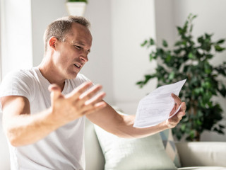 Bad news. Depressed mature man holding paper
