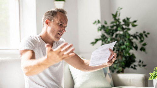 Bad news. Depressed mature man holding paper