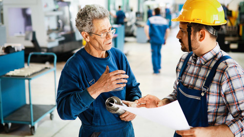 Factory worker discussing data with supervisor in metal factory