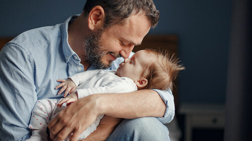 Middle age Caucasian father kissing sleeping newborn baby girl.