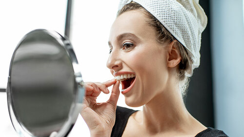Woman wearing plastic form for teeth at home