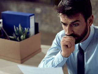 Young distraught businessman reading a notice after being fired at work,