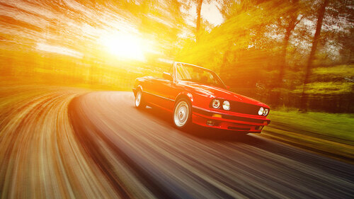 Classic red convertible sport car driving fast on the open road