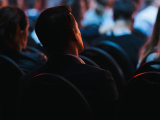 Speaker on the stage with Rear view of Audience in the conferenc