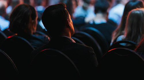 Speaker on the stage with Rear view of Audience in the conferenc