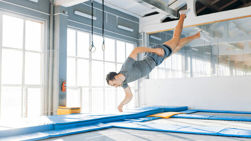 active young man is landing on mats during workout.