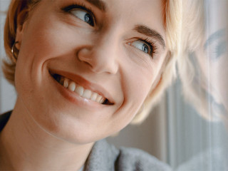 Smiling attractive woman is standing near window