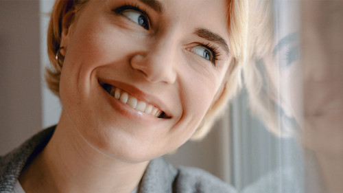 Smiling attractive woman is standing near window