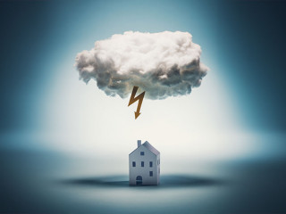 Paper house standing under a white cloud with yellow lightning