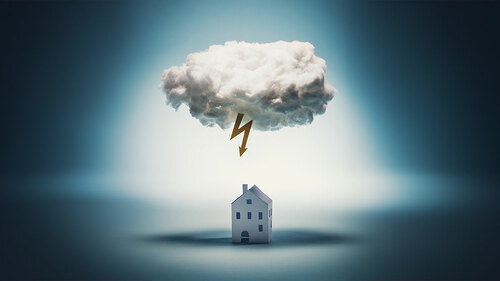 Paper house standing under a white cloud with yellow lightning