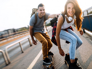 Young attractive couple riding skateboards and having fun