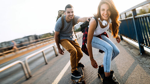 Young attractive couple riding skateboards and having fun