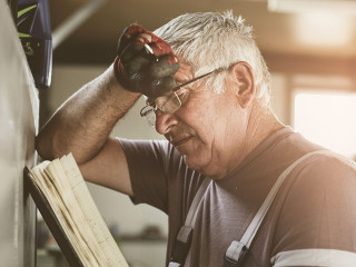 Senior man in workshop. Worried man reading his planner.